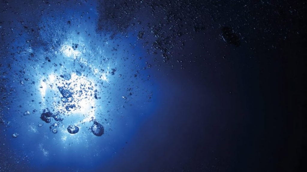 Arctic Frontiers - Bubbles rising towards a bright light underwater, surrounded by deep blue and black shadows—an evocative scene from Arctic Frontier Partner pictures.