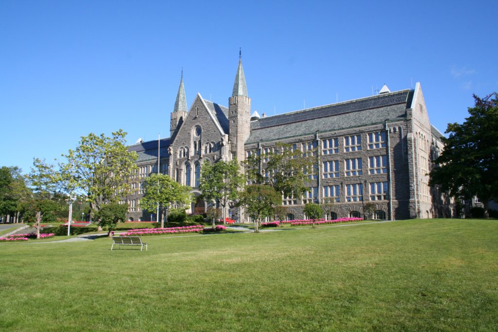 Arctic Frontiers - Large stone building with tall towers, arched windows, and a green lawn under a clear blue sky—a perfect setting reminiscent of Arctic Frontier Partner pictures.