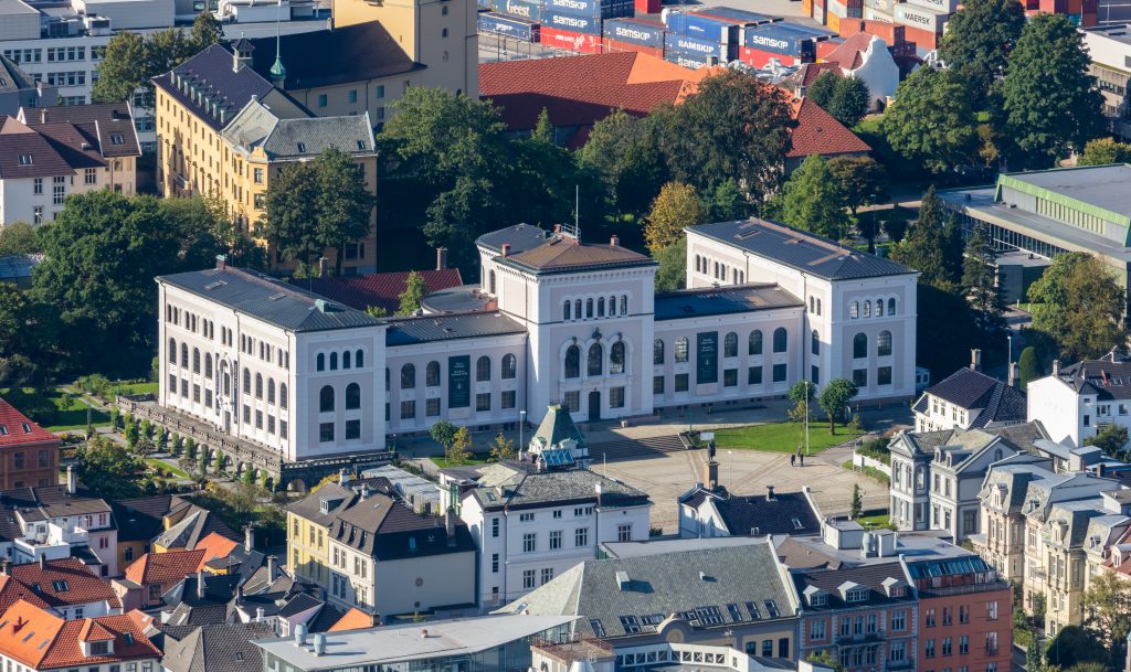 Arctic Frontiers - Large white building with arched windows, surrounded by trees and city buildings, viewed from above—an iconic scene often featured in Arctic Frontier Partner pictures.