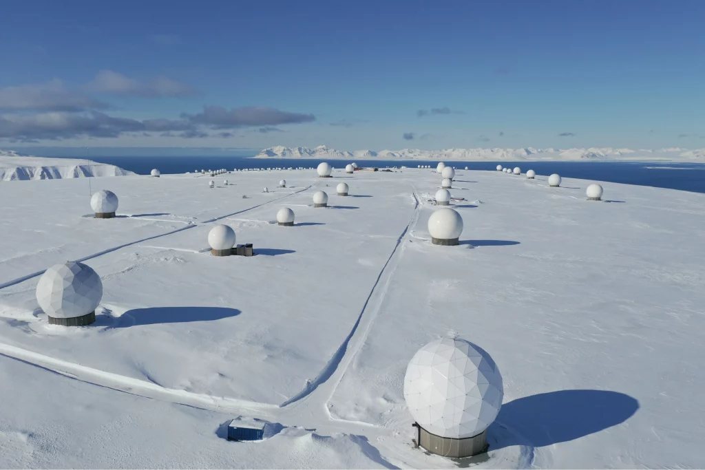 Arctic Frontiers - Snow-covered landscape with many white spherical satellite domes under a clear blue sky—an iconic scene captured by Arctic Frontier Partner pictures.