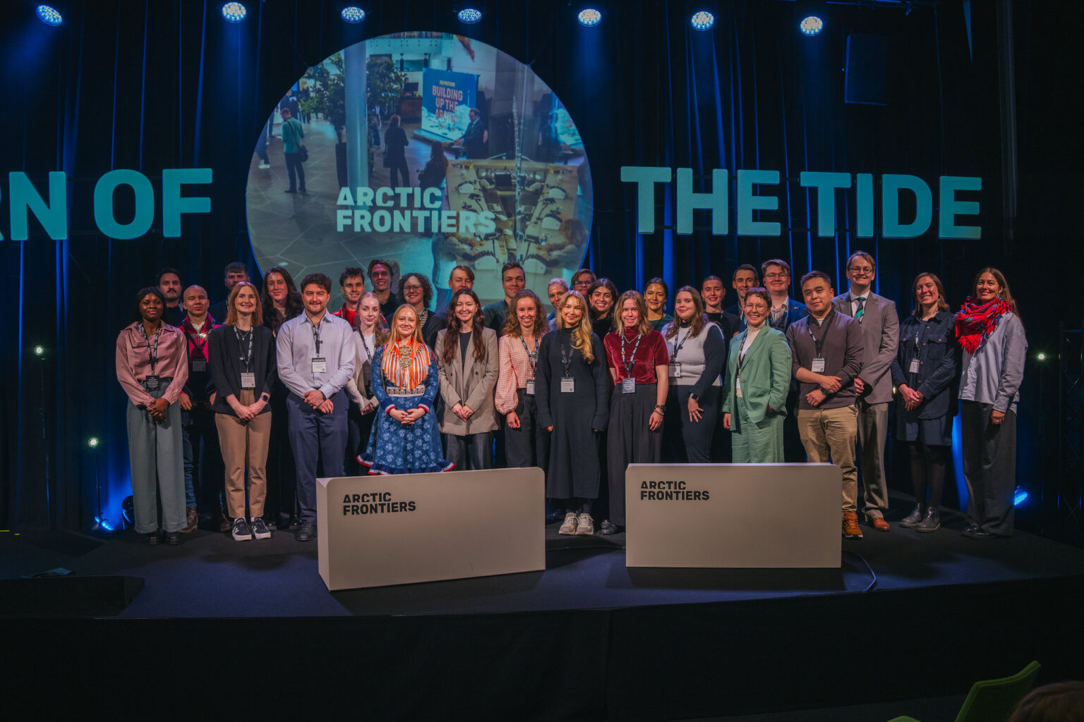 Arctic Frontiers - A group of people pose on stage at the Arctic Frontiers – Young Student Forum event, standing in front of two lecterns.