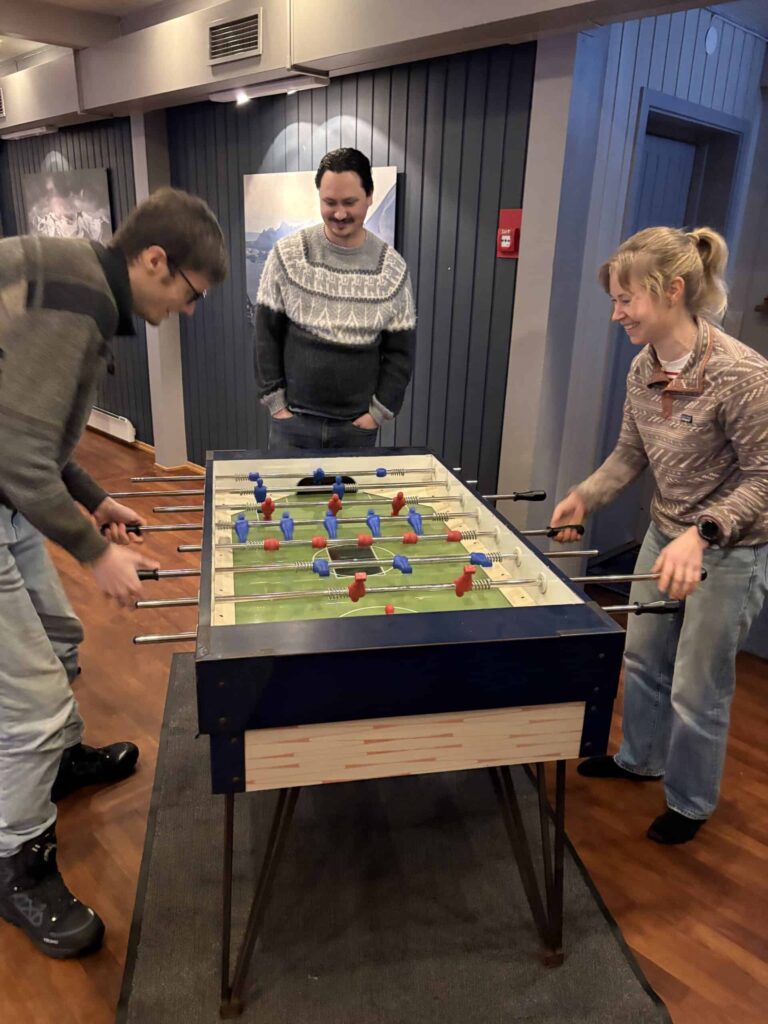 Arctic Frontiers - Three people play table football indoors, two playing and one watching, all smiling and enjoying the game.